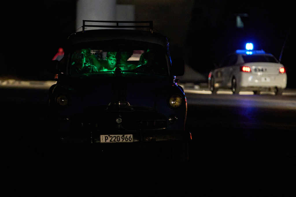 People are seen waiting in a car in the dark during a blackout in Havana, Cuba, Saturday, March 21, 2026. (AP Photo/Ramon Espinosa)