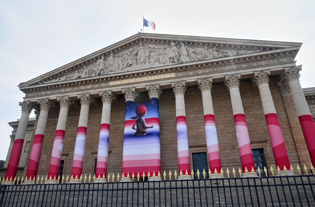 The French National Assembly is draped with the artwork "Marianne rêve" ("Marianne Dreams") by French street artist Seth, depicting Marianne the symbol of the French Republic, before lawmakers vote later on final approval of a bill allowing adults with incurable illnesses to receive lethal medication, in Paris, Wednesday, July 15, 2026. (AP Photo/Michel Euler)