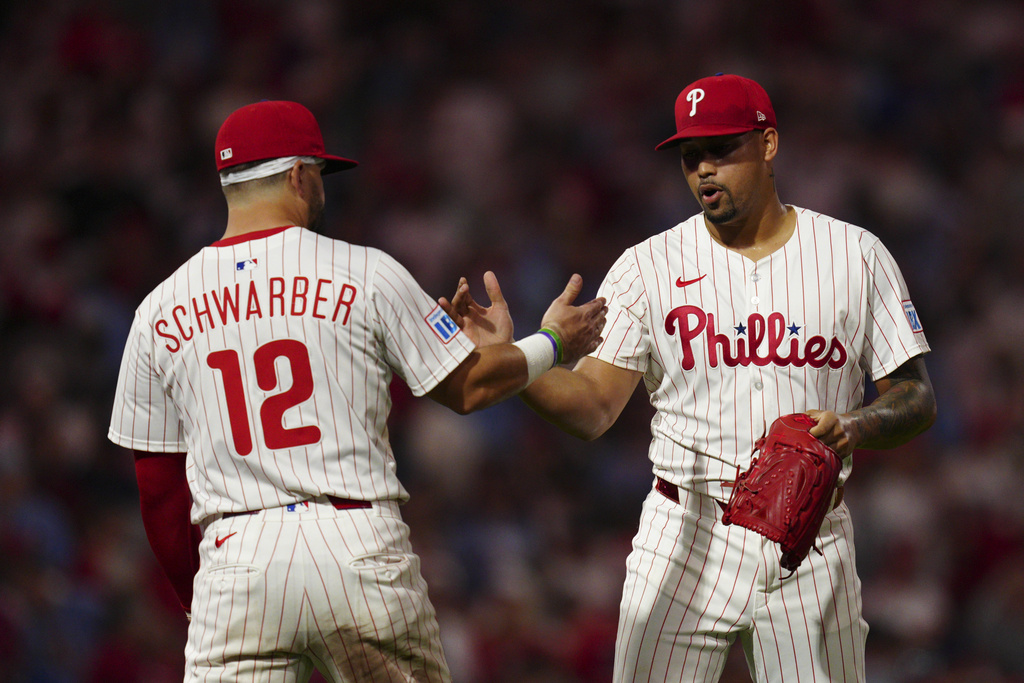 Philadelphia Phillies pitcher Jhoan Duran, right, and Kyle Schwarber (12) celebrate their team's victory after a baseball game against the Washington Nationals, Saturday, Aug. 23, 2025, in Philadelphia. (AP Photo/Derik Hamilton)