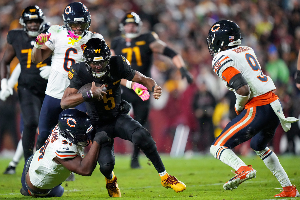 Washington Commanders quarterback Jayden Daniels (5) is tackled by Chicago Bears defensive lineman Chris Williams (91) with cornerback Kyler Gordon (6) and safety Jaquan Brisker (9) nearby during the first half of an NFL football game Monday, Oct. 13, 2025, in Landover, Md. (AP Photo/Stephanie Scarbrough)