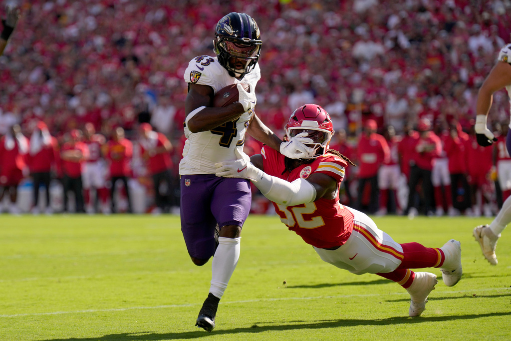 Baltimore Ravens running back Justice Hill (43) slips past Kansas City Chiefs linebacker Nick Bolton (32) for a touchdown during the first half of an NFL football game Sunday, Sept. 28, 2025, in Kansas City, Mo. (AP Photo/Charlie Riedel)