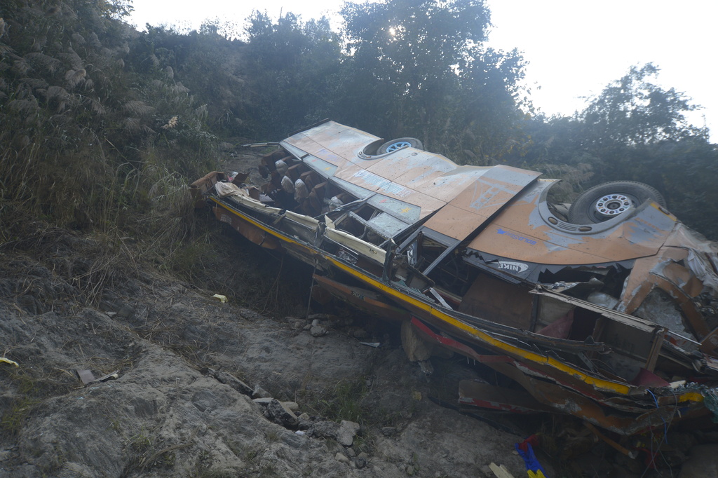 The wreckage of a bus is seen on the bank of the Trishuli River after it drove off a mountain highway near Benighat, west of the capital, Kathmandu, Nepal, Monday, Feb. 23, 2026. (AP Photo/Bijay Rai)