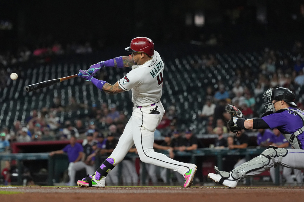 Arizona Diamondbacks' Ketel Marte (4) hits a run-scoring single as Colorado Rockies catcher Brett Sullivan reaches for the ball during the first inning of a baseball game, Wednesday, Aug. 12, 2026, in Phoenix. (AP Photo/Ross D. Franklin)