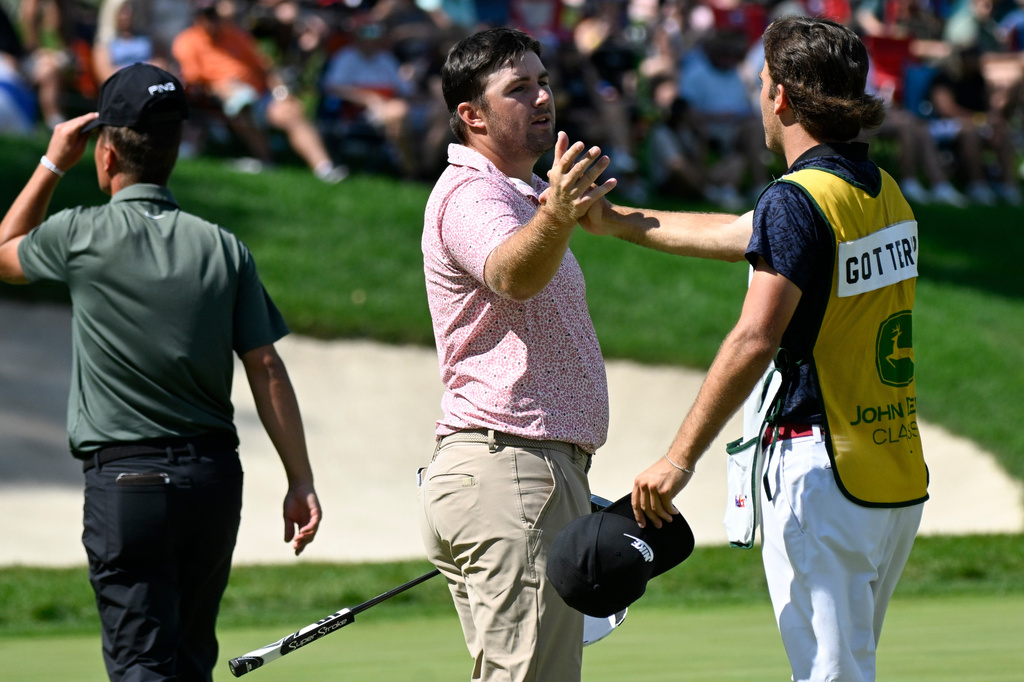 Chris Gotterup, center, high fives his brother and caddie Patrick Gotterup, right, after finishing the 18th hole during the final round of the John Deere Classic golf tournament, Sunday, July 5, 2026, in Silvis, Ill. (AP Photo/Matt Marton)