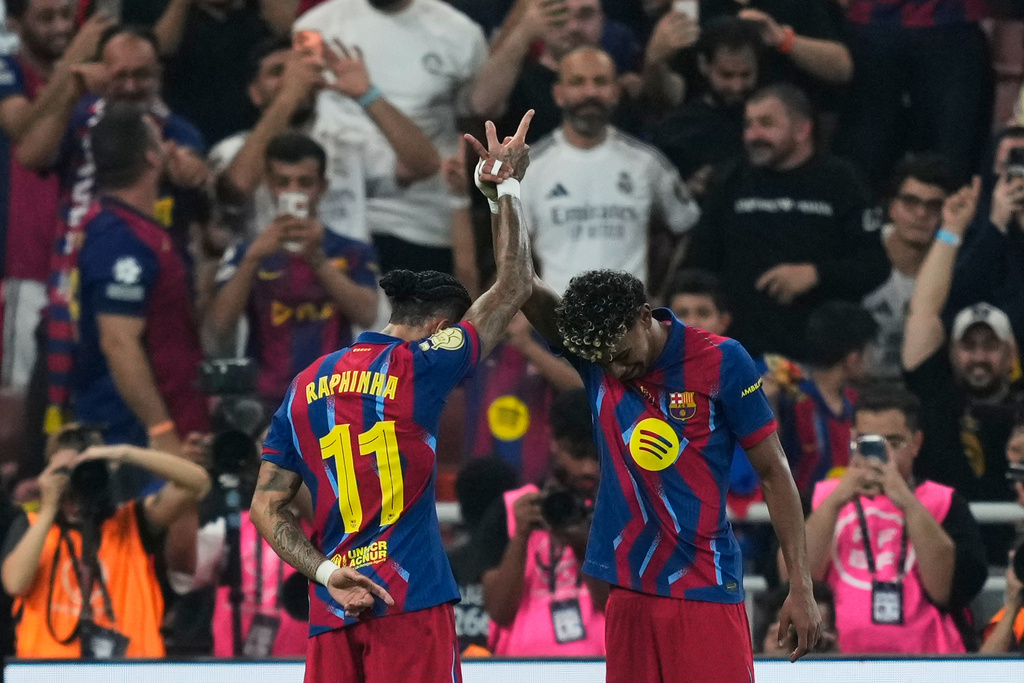 Barcelona's Raphinha, left, celebrates with teammate Lamine Yamal after scoring the opening goal during the Spanish Super Cup final soccer match against Real Madrid at King Abdullah Sports City Stadium in Jeddah, Saudi Arabia, Sunday, Jan. 11, 2026. (AP Photo/Altaf Qadri)