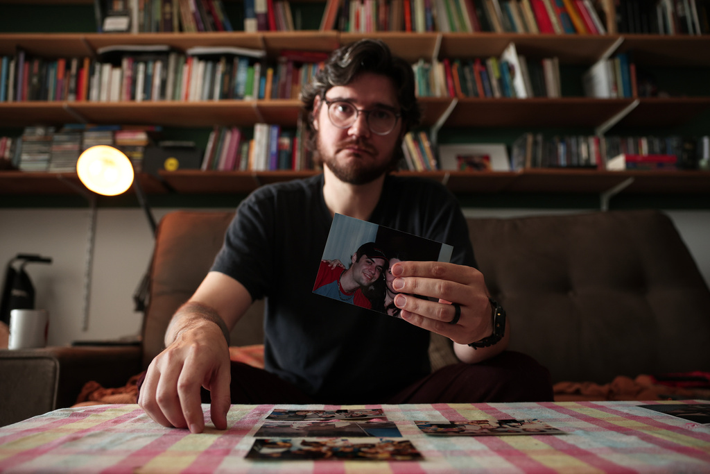 Teacher and businessman Diego Orsi shows a photo of his late cousin Henrique, who died of COVID-19, during an interview at his home, in Sao Paulo, Wednesday, Nov. 19, 2025. (AP Photo/Ettore Chiereguini)