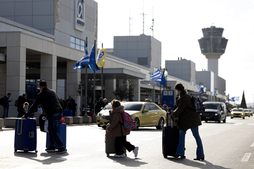 Passengers make their way to Athens' Eleftherios Venizelos international airport in Athens, Greece, Sunday, Jan. 4, 2026, as many flights were disrupted across Greece. (AP Photo/Yorgos Karahalis)