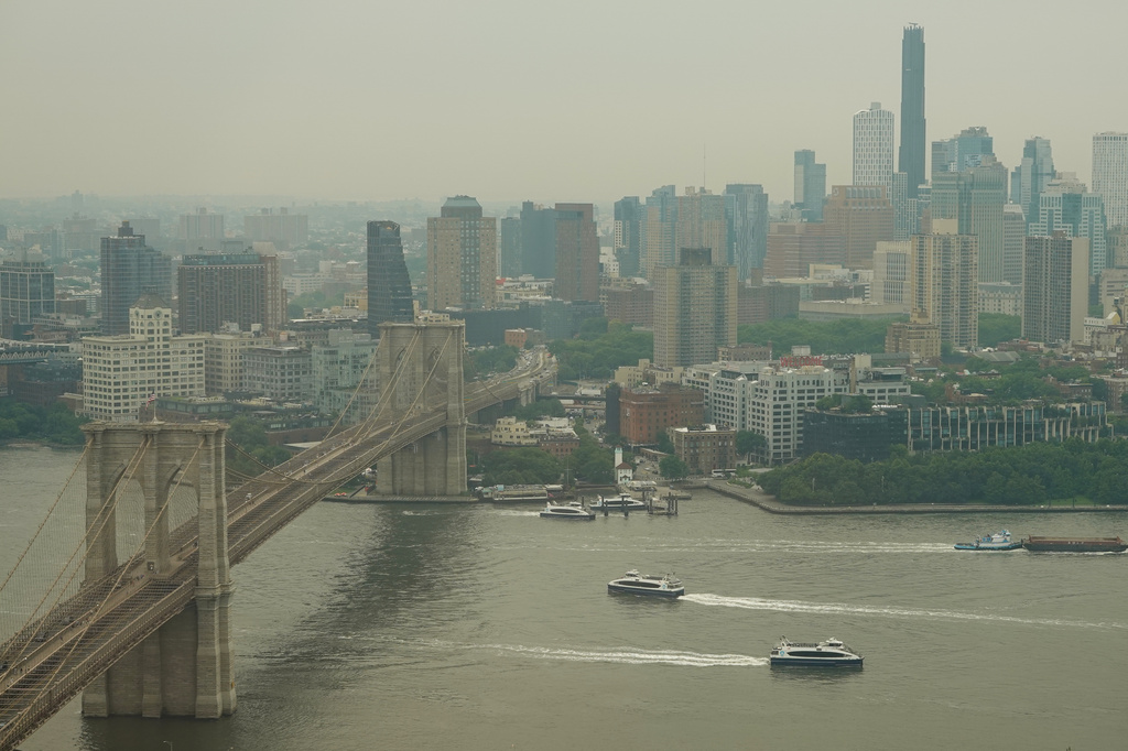 Boats maneuver the East River near the Brooklyn Bridge as smoke from wildfires blankets the sky Thursday, July 16, 2026, in New York. (AP Photo/Alyssa Goodman)