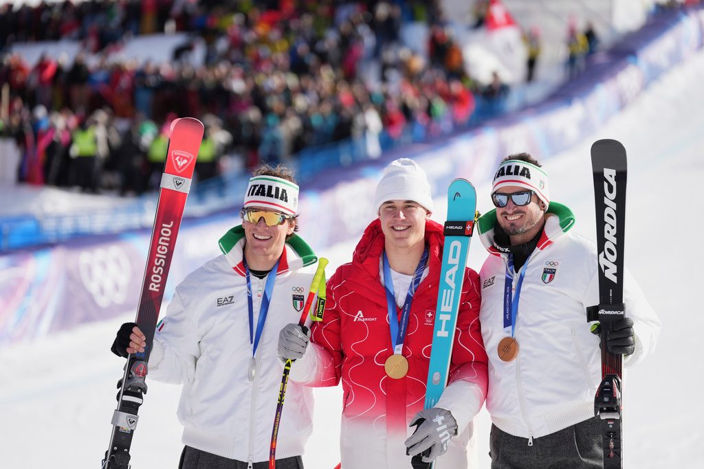 Switzerland's Franjo von Allmen, gold medal in an alpine ski men's downhill race, center, celebrates with silver medalist Italy's Giovanni Franzoni, left, and bronze medalist Italy's Dominik Paris at the 2026 Winter Olympics, in Bormio, Italy, Saturday, Feb. 7, 2026. (AP Photo/Rebecca Blackwell)