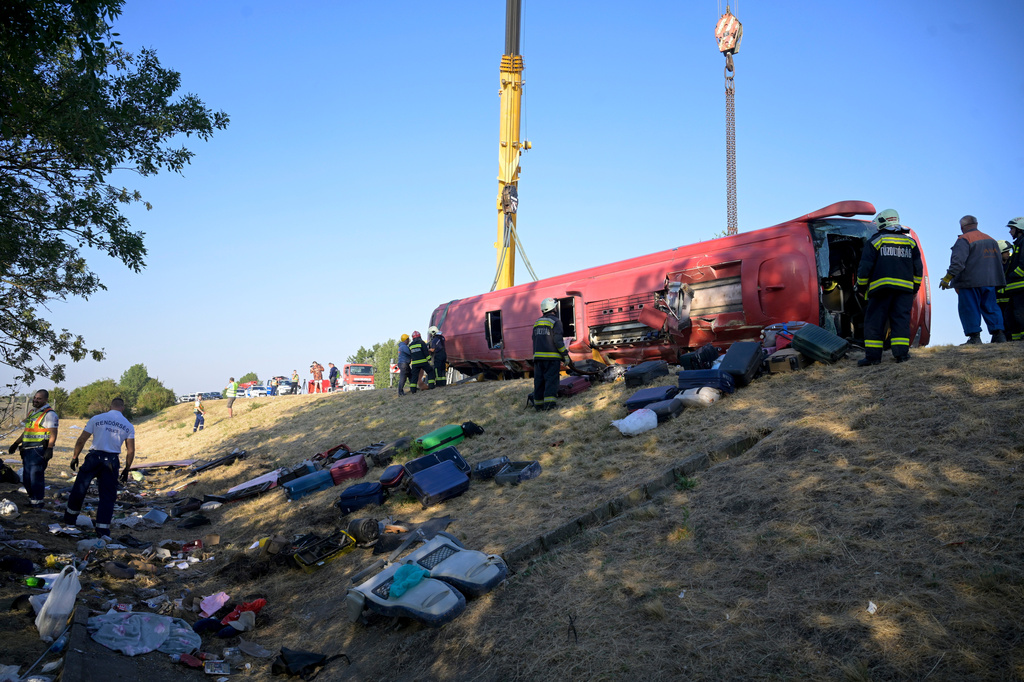 Emergency services attend the scene after a passenger bus went off the road and overturned in a ditch along a highway between Mezokeresztes and Mezonagymihaly in Hungary, Sunday, Aug. 16, 2026. (Zoltan Mathe/MTI via AP)