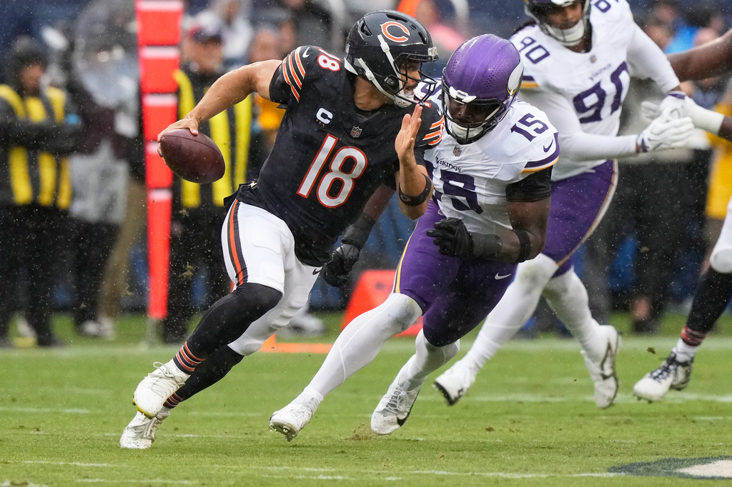 Chicago Bears quarterback Caleb Williams (18) scrambles as Minnesota Vikings outside linebacker Dallas Turner (15) defends during the first half of an NFL football game in Chicago, Sunday, Sept. 20, 2026. (AP Photo/Nam Y. Huh)
