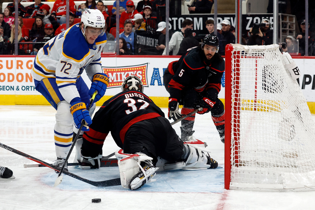 Buffalo Sabres' Tage Thompson (72) tries to get the puck as it slips by Carolina Hurricanes goaltender Brandon Bussi (32) with Hurricanes' Jalen Chatfield (5) nearby during the third period of an NHL hockey game in Raleigh, N.C., Monday, Jan. 19, 2026. (AP Photo/Karl DeBlaker)