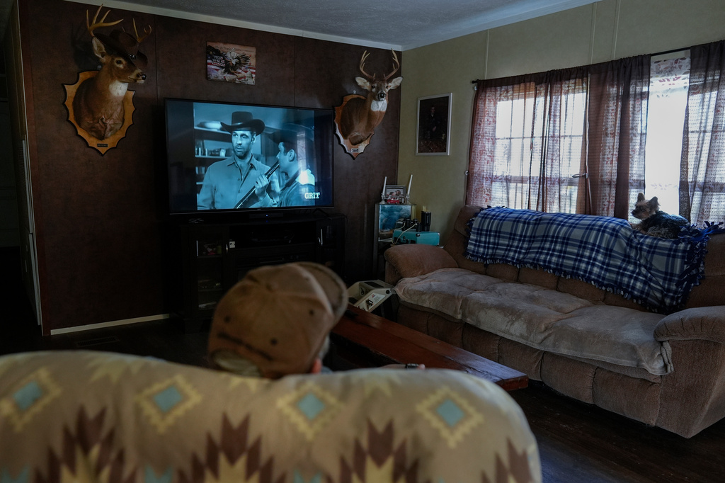 Retired railroad worker and Army veteran Charles "Duke" Hodge watches old Westerns with Sophie, one of his two Yorkies, in his home at the Olde Oak RV Park and Campground where he lives and works in West Columbia, W.Va., Tuesday, March 17, 2026. (AP Photo/Carolyn Kaster)