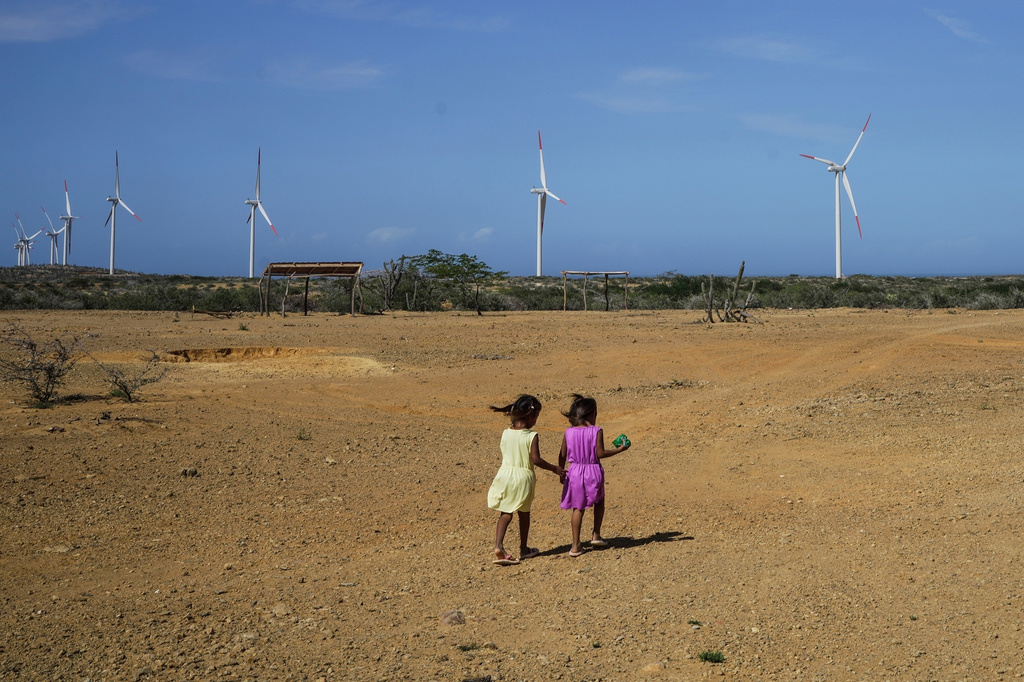 FILE - Two girls from the Wayuu Indigenous community play near a wind farm on the outskirts of Cabo de la Vela, Colombia, Feb. 7, 2025. (AP Photo/Ivan Valencia, File)