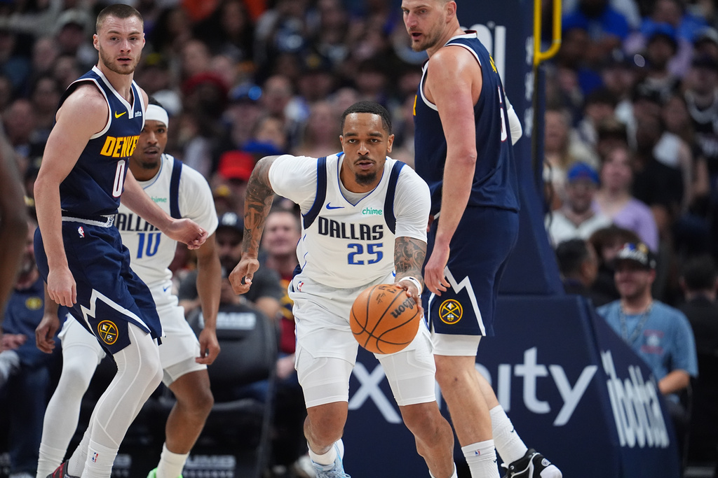 Dallas Mavericks forward P.J. Washington, center, collects a loose ball as Denver Nuggets guard Christian Braun, left, and center Nikola Jokic defend in the first half of an NBA basketball game Wednesday, March 25, 2026, in Denver. (AP Photo/David Zalubowski)