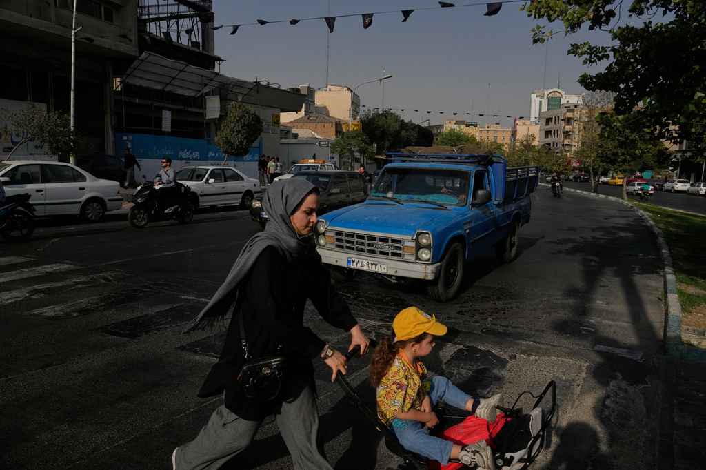 A woman crosses a street with a girl in downtown Tehran, Iran, Wednesday, July 22, 2026. (AP Photo/Vahid Salemi)