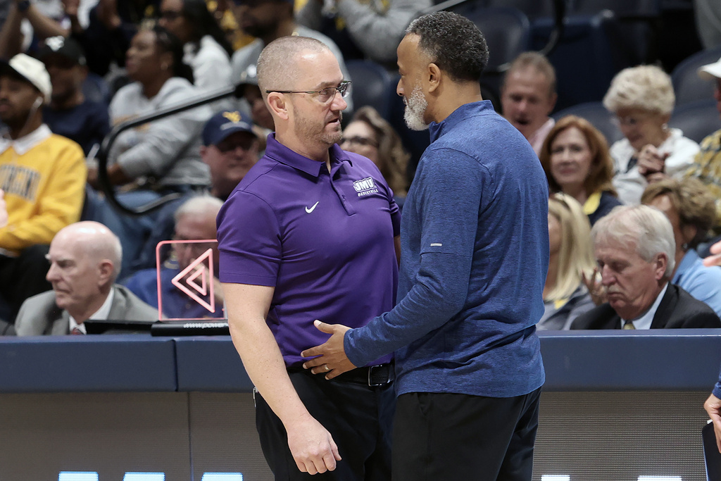 James Madison coach Sean O'Regan, left, and Kentucky coach Kenny Brooks greet each other after a first round game in the NCAA college basketball tournament, Saturday, March 21, 2026, in Morgantown, W.Va. (AP Photo/Kathleen Batten)