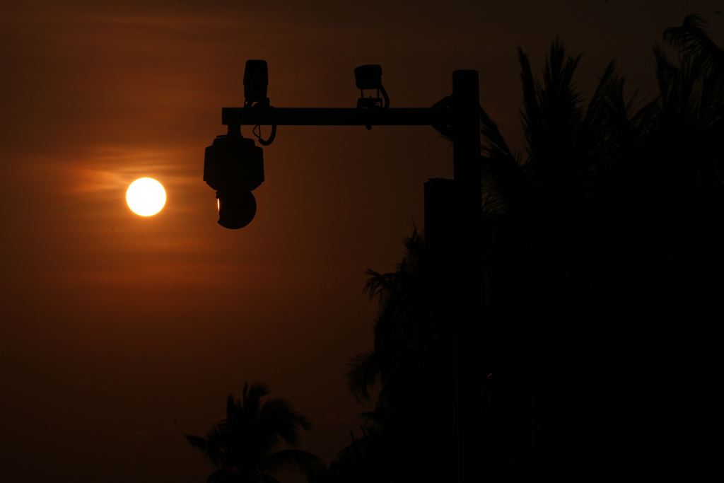 The sun sets near security cameras along a beach near Sanya city in southern China's Hainan province on Saturday, April 26, 2025. (AP Photo/Ng Han Guan)