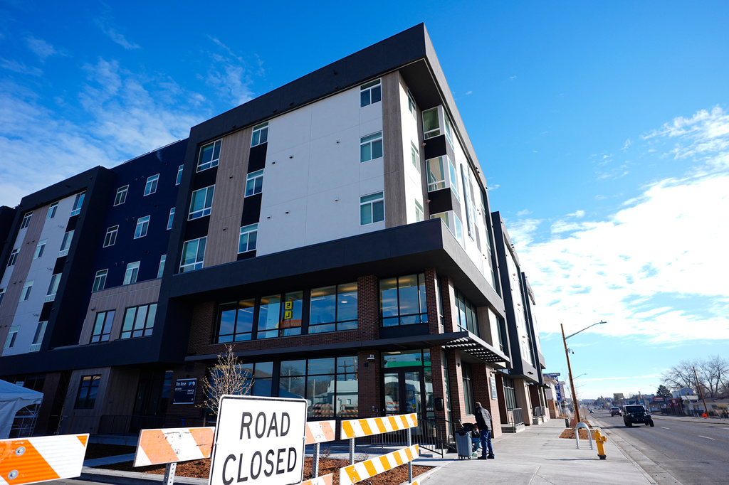 FILE - A person sweeps outside during the grand opening of the Rose on Colfax, a new affordable housing community with a co-located childcare center in the East Colfax neighborhood, Jan. 24, 2024, in Denver. (AP Photo/David Zalubowski, File)