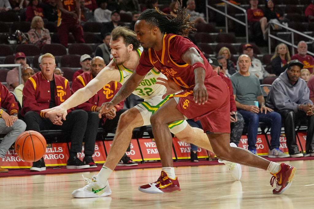 Oregon center Nate Bittle (32) and Southern California guard Kam Woods (13) battle for the ball during the first half of an NCAA college basketball game Saturday, Feb. 21, 2026, in Los Angeles. (AP Photo/Damian Dovarganes)