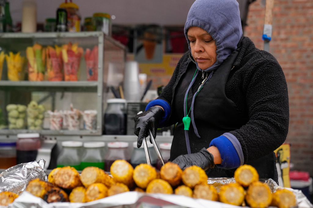 Ofelia Herrera, originally from Mexico, grills corn at her family's street food stand in Little Village, Nov. 8, 2025, in Chicago. (AP Photo/Erin Hooley)
