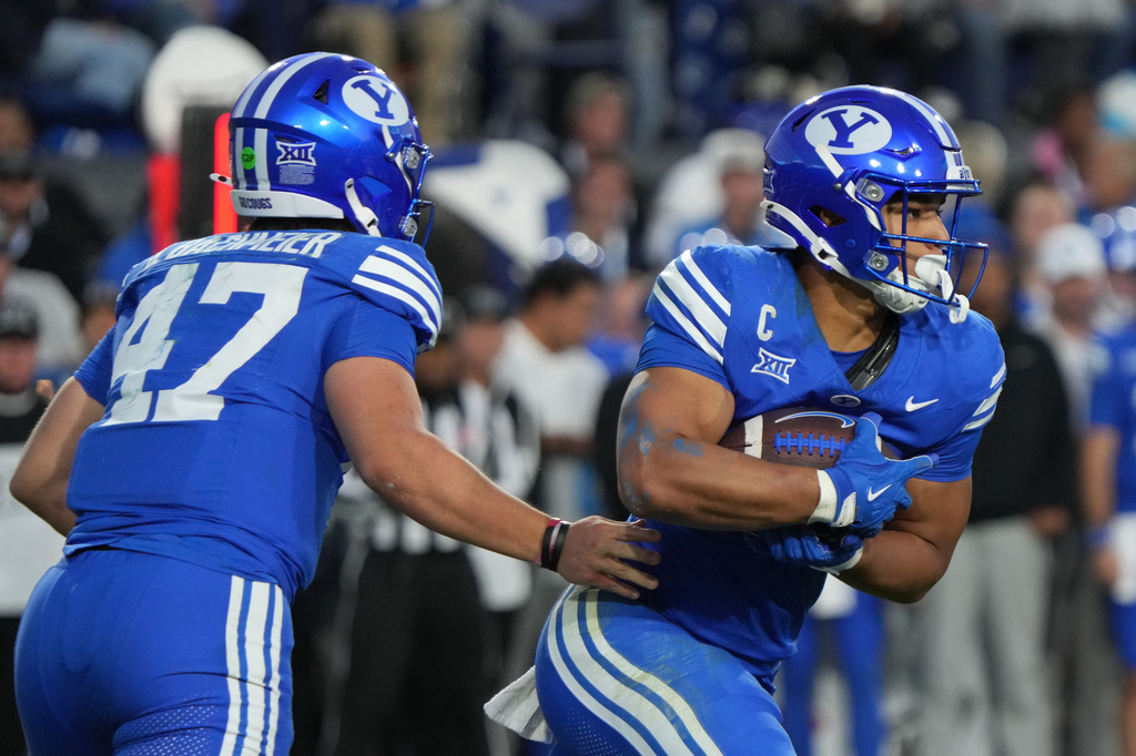 FILE - BYU quarterback Bear Bachmeier (47) hands the ball off to BYU running back LJ Martin (4) during the first half of an NCAA college football game against Utah, on Oct. 18, 2025, in Provo, Utah. (AP Photo/George Frey, File)
