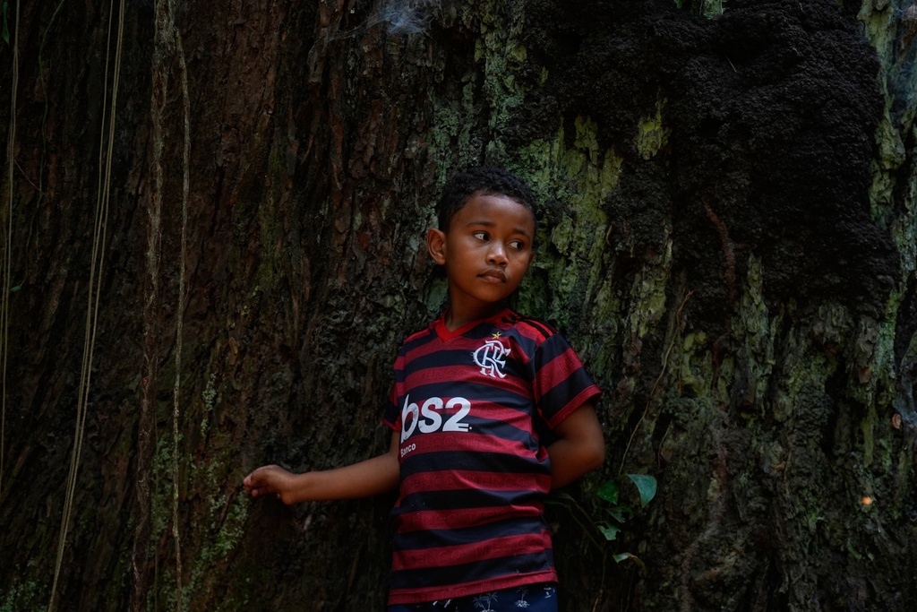 Riquelme listens to his grandpa Edson Coelho during a tour of a quilombola, an Afro-descendant community called Menino Jesus in Acara, Brazil, Tuesday, Nov. 18, 2025. (AP Photo/Fernando Llano)