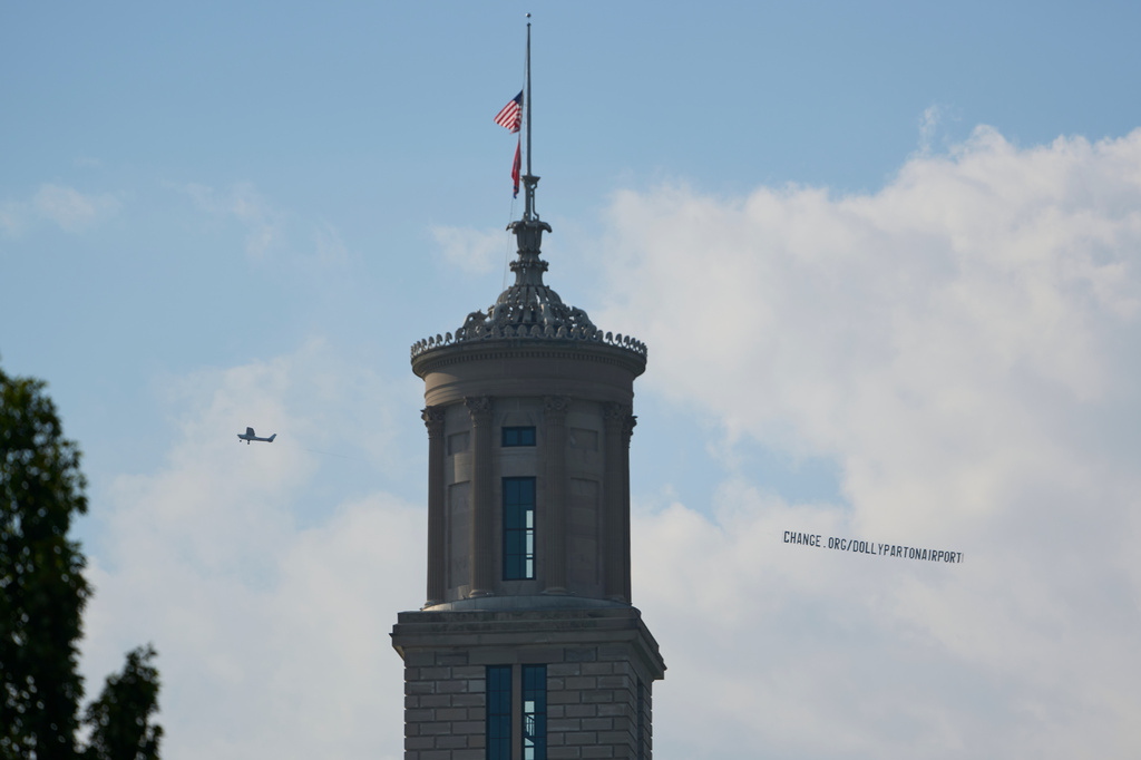A plane flies over Nashville, Tenn., towing a banner reading “change.org/DollyPartonAirport” as part of an effort to rename the airport after Dolly Parton, Friday, Aug. 28, 2026. (AP Photo/George Walker IV)