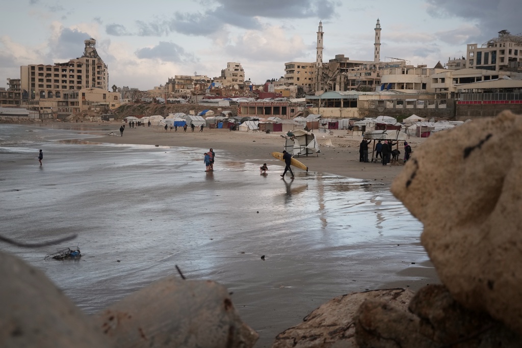 A Palestinian surfer carries his board into the sea along the shoreline in Gaza City, Sunday, Dec. 28, 2025. (AP Photo/Jehad Alshrafi)