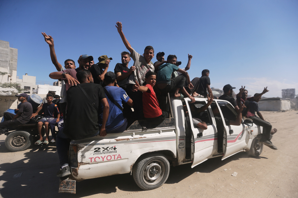 Displaced Palestinians wave to the camera as they move in the direction of Gaza City, in the northern Gaza Strip, Friday, Oct. 10, 2025, after Israel and Hamas have agreed to a pause in their war and the release of the remaining hostages. (AP Photo/Yousef Al Zanoun)