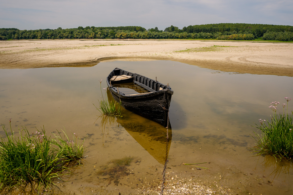 A boat is banked on the sand in an area usually submerged in water along the Danube River during low water levels in Rasova, Romania, Monday, Aug. 3 2026. (AP Photo/Andreea Alexandru)