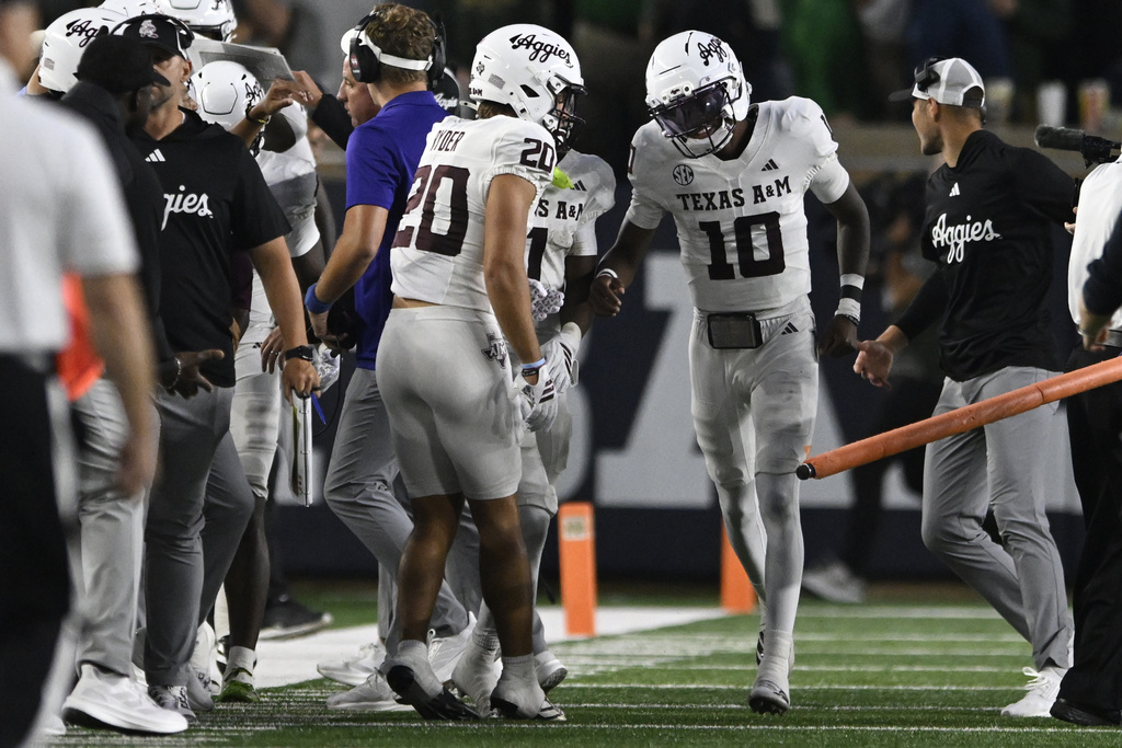 Texas A&M quarterback Marcel Reed (10) celebrates with teammates on the sideline after wide receiver Mario Craver caught a touchdown pass during the first quarter of an NCAA football game against Notre Dame, Saturday, Sept. 13, 2025, in South Bend, Ind. (AP Photo/Paul Beaty)
