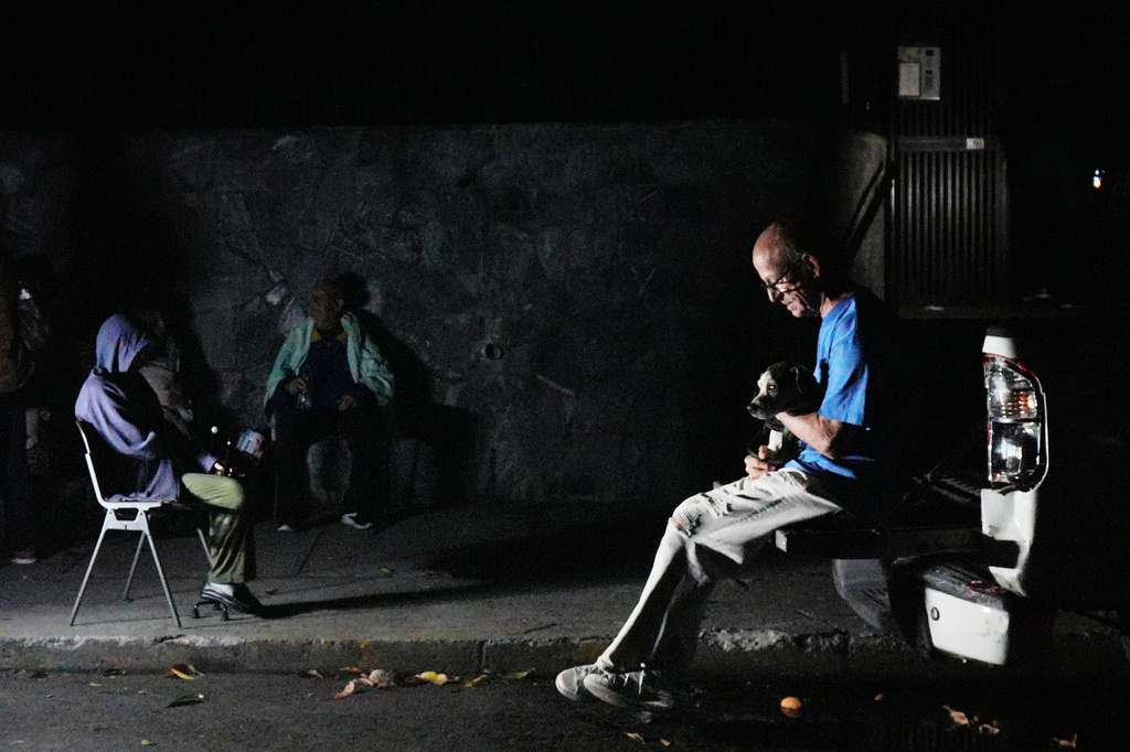 A man sits with his dog outside his home after an earthquake in Caracas, Venezuela, Wednesday, June 24, 2026. (AP Photo/Adrian Naranjo)