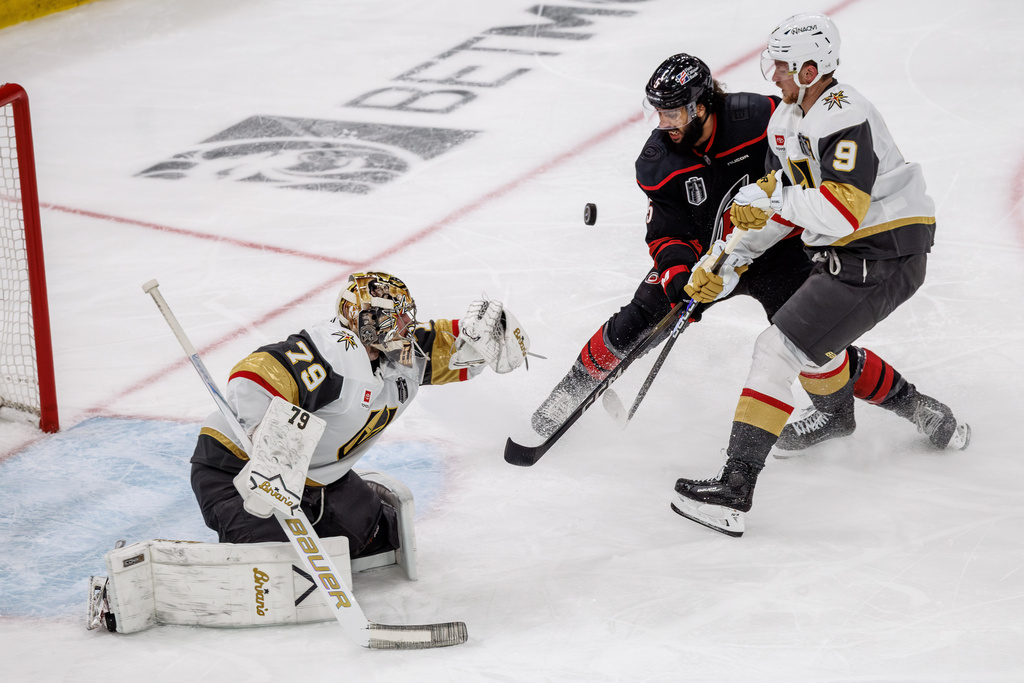 Vegas Golden Knights' Carter Hart (79) knocks a puck away from the net as Golden Knights' Jack Eichel (9) and Carolina Hurricanes' Jalen Chatfield (5) battle during the second period of Game 2 of the NHL hockey Stanley Cup Final series in Raleigh, N.C., Thursday, June 4, 2026. (AP Photo/Ben McKeown)
