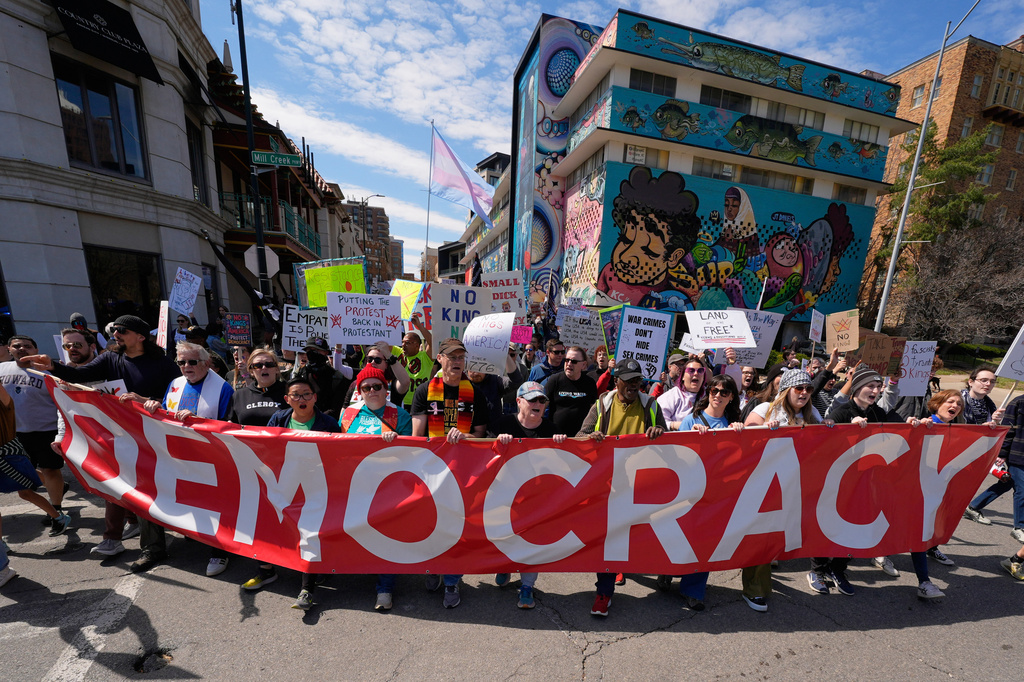 Demonstrators march through the Country Club Plaza shopping district during a "No Kings" protest Saturday, March 28, 2026, in Kansas City, Mo. (AP Photo/Charlie Riedel)