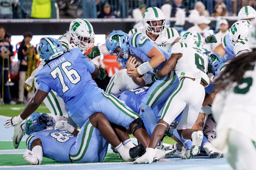 Tulane quarterback Jake Retzlaff (12) rushes for a touchdown against Charlotte defensive back Cary Grant (9) during the first half of an NCAA college football game in New Orleans, Saturday, Nov. 29, 2025. (AP Photo/Matthew Hinton)