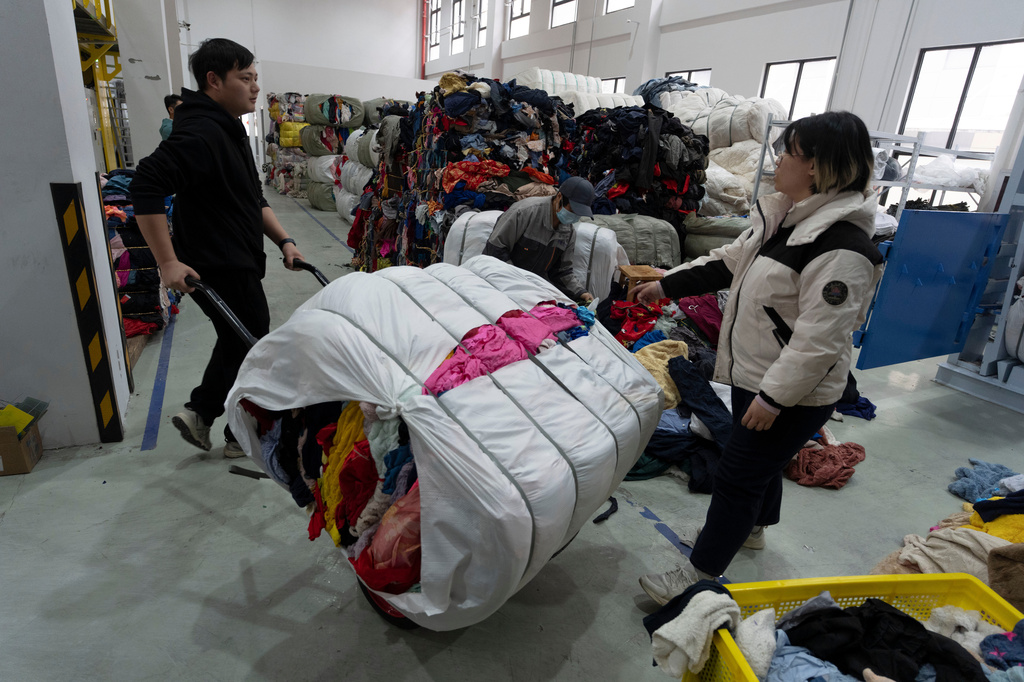 Workers move piles of used clothes at a textile sorting facility that employ's Databeyond's Fastsort-Textile AI sorting machine in Zhangjiagang in eastern China's Jiangsu province on March 20, 2026. (AP Photo/Ng Han Guan)