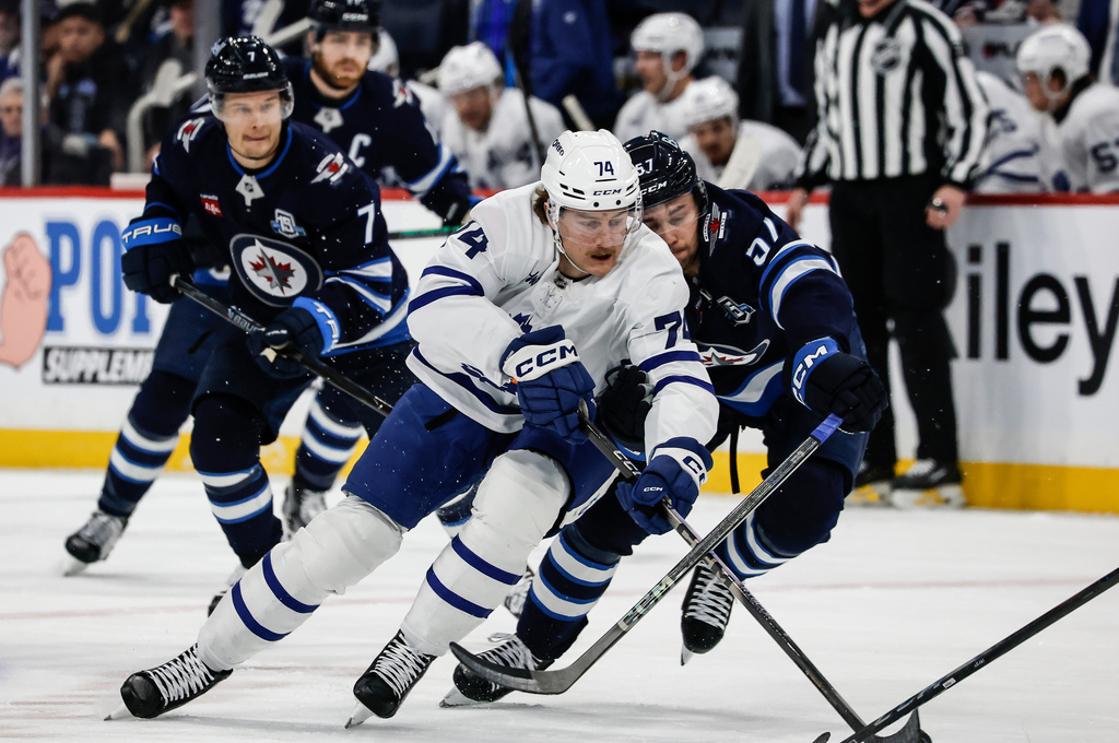 Winnipeg Jets' Elias Salomonsson (57) defends against Toronto Maple Leafs' Bobby McMann (74) who breaks toward the net during first-period NHL hockey game action in Winnipeg, Manitoba, Saturday, Jan. 17, 2026. (John Woods/The Canadian Press via AP)