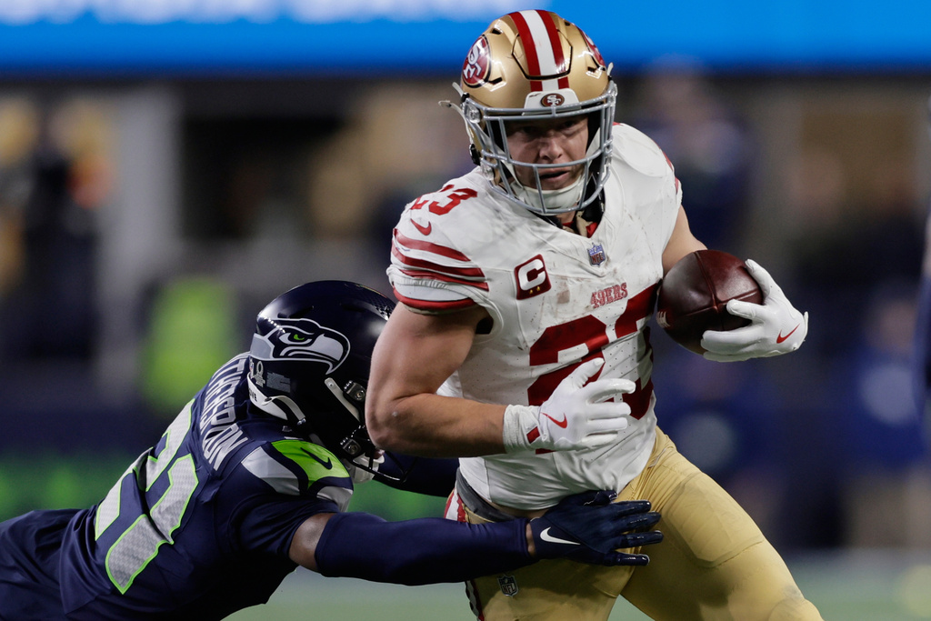 San Francisco 49ers running back Christian McCaffrey (23) tries to get past the Seattle Seahawks cornerback Devon Witherspoon during the first half of an NFL football divisional playoff game Saturday, Jan. 17, 2026, in Seattle. (AP Photo/John Froschauer)