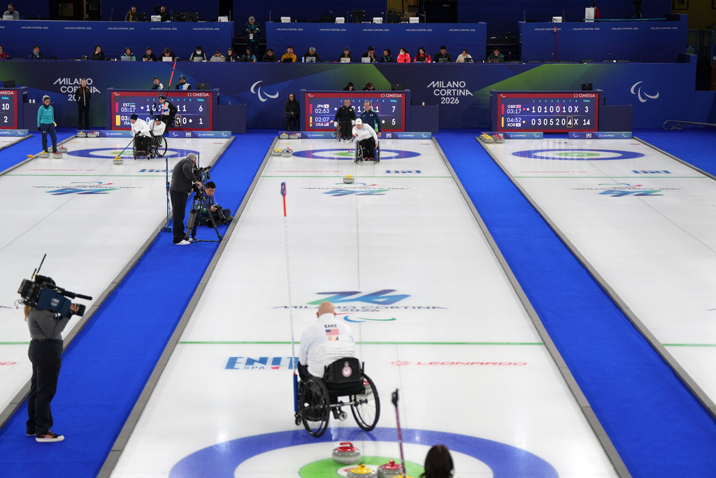 Steve Emt, foreground, and Laura Dwyer, center, of the United States, compete against Yoji Nakajima and Aki Ogawa, of Japan, in a wheelchair curling mixed doubles round robin session at the 2026 Winter Paralympics, in Cortina d'Ampezzo, Italy, Thursday, March 5, 2026. (AP Photo/Evgeniy Maloletka)