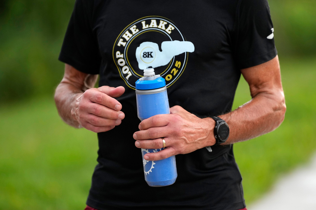 Paul Grinvalds, of West Des Moines, Iowa, holds a water bottle after a run with the Raccoon River Running Club, Sunday, Aug. 9, 2026, in West Des Moines, Iowa. (AP Photo/Charlie Neibergall)