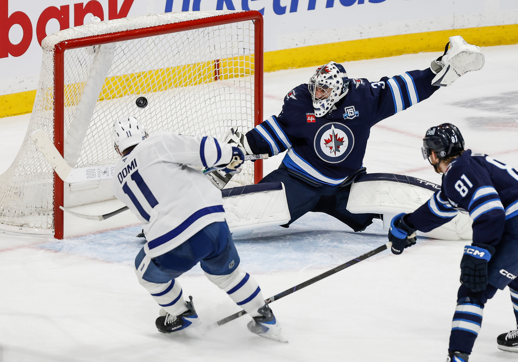 Toronto Maple Leafs' Max Domi (11) scores the game-winning overtime goal against Winnipeg Jets goaltender Connor Hellebuyck (37) during NHL action in Winnipeg, Saturday, Jan. 17, 2026. (John Woods/The Canadian Press via AP)