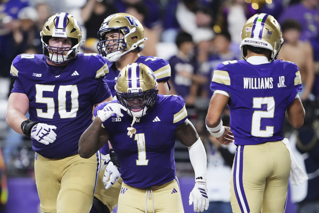 Washington running back Jonah Coleman (1) celebrates a touchdown with teammates, including offensive lineman Carver Willis (50) and quarterback Demond Williams Jr. (2) during the first half of an NCAA college football game against UC Davis, Saturday, Sept. 6, 2025, in Seattle. (AP Photo/Lindsey Wasson)