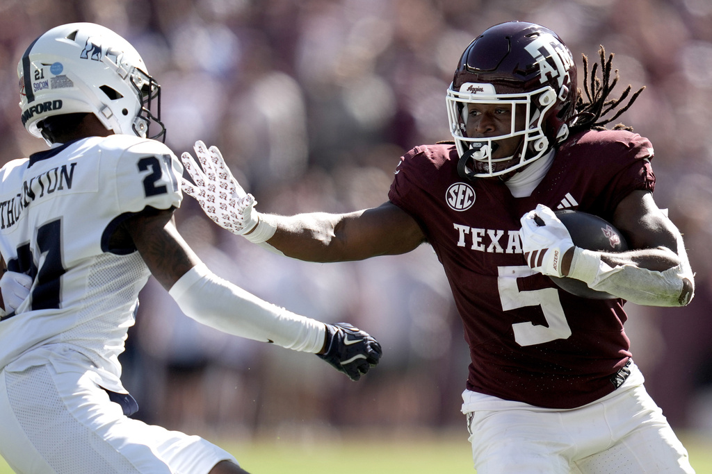 Texas A&amp;M running back Amari Daniels (5) stiff arms Samford cornerback Malik Thornton (21) during a long run from scrimmage during the second quarter of an NCAA college football game Saturday, Nov. 22, 2025, in College Station, Texas. (AP Photo/Sam Craft)
