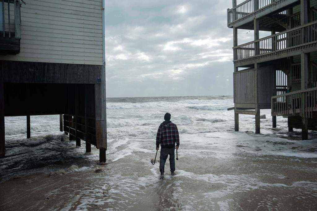 A worker who is reinforcing a home at risk of falling into the ocean looks out toward the waves as a storm approaches Friday, Oct. 10, 2025, in Buxton, N.C. (AP Photo/Allison Joyce)