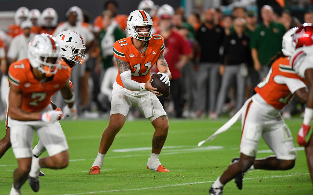 Miami quarterback Carson Beck (11) receives the ball during the first half of an NCAA college football game against Louisville, Friday, Oct. 17, 2025, in Miami Gardens, Fla. (AP Photo/Michael Laughlin)