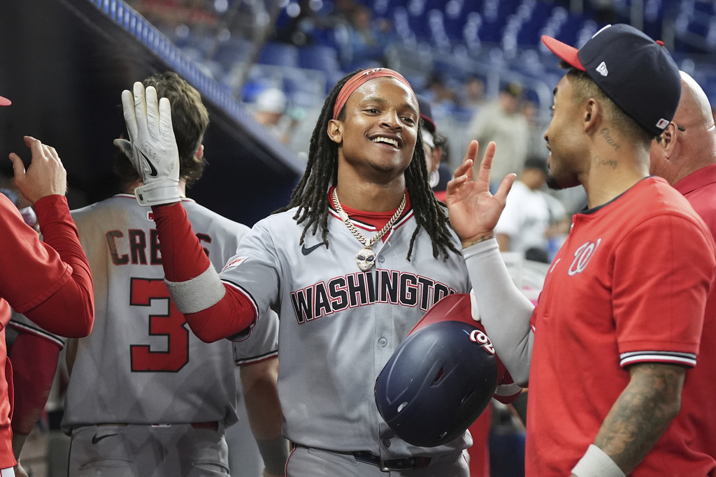 Washington Nationals' CJ Abrams, center, is congratulated in the dugout after scoring on a single hit by Josh Bell during the fifth inning of a baseball game against the Miami Marlins, Monday, Sept. 8, 2025, in Miami. (AP Photo/Lynne Sladky)