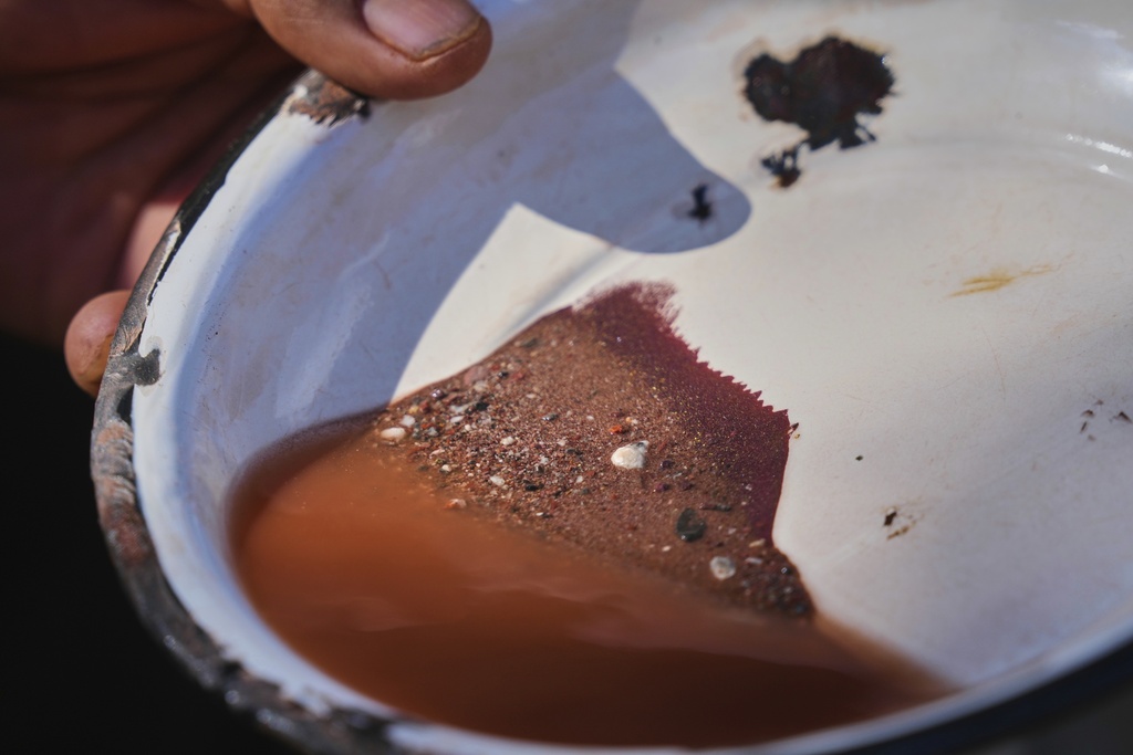 Hugo Flores looks at some samples of mercury ore, at the top, to calculate the cooking time in the furnace in San Joaquin, Mexico, Tuesday, Aug. 19, 2025. (AP Photo/Fernando Llano)