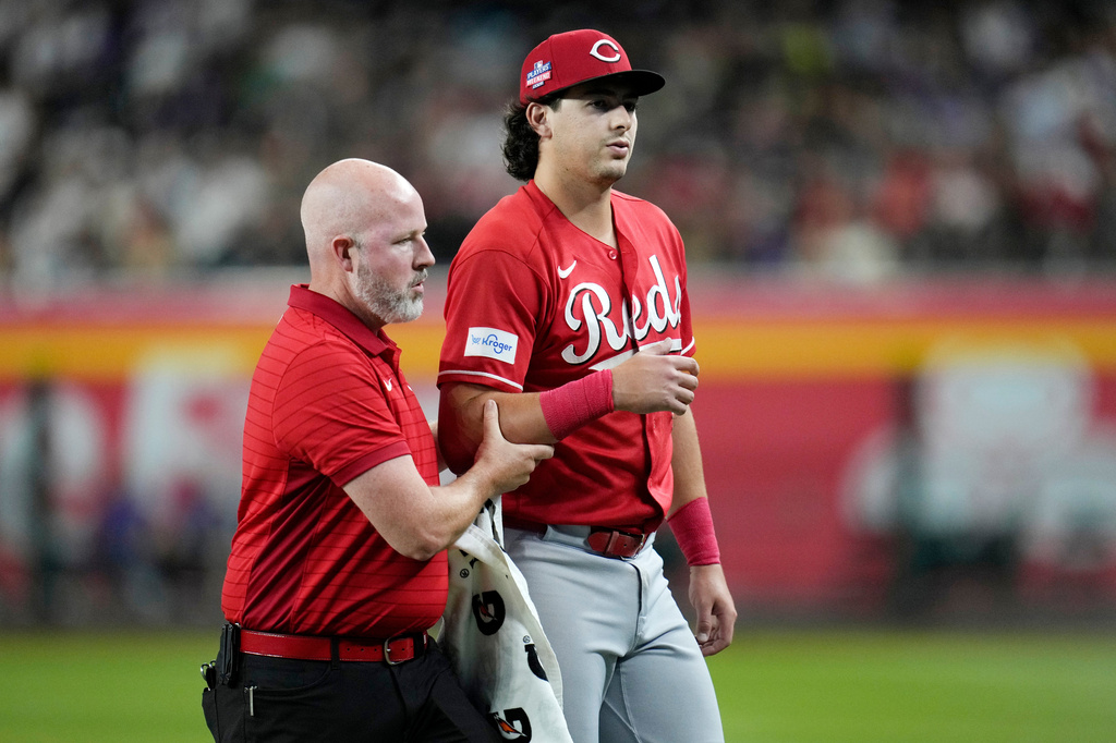 Injured Cincinnati Reds left fielder Michael Toglia, right, is helped off the field by a member of the Reds training staff during the first inning of a baseball game against the Arizona Diamondbacks, Friday, Aug. 21, 2026, in Phoenix. (AP Photo/Ross D. Franklin)