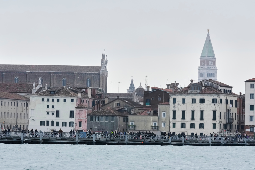 Mourners walk on the 'Votif' Bridge, a 407m temporary floating bridge connecting the city to the cemetery on the island of San Michele, to pay respects to their dead on All Soul's Day, in Venice, Italy, Sunday, Nov. 2, 2025. (AP Photo/Luca Bruno)